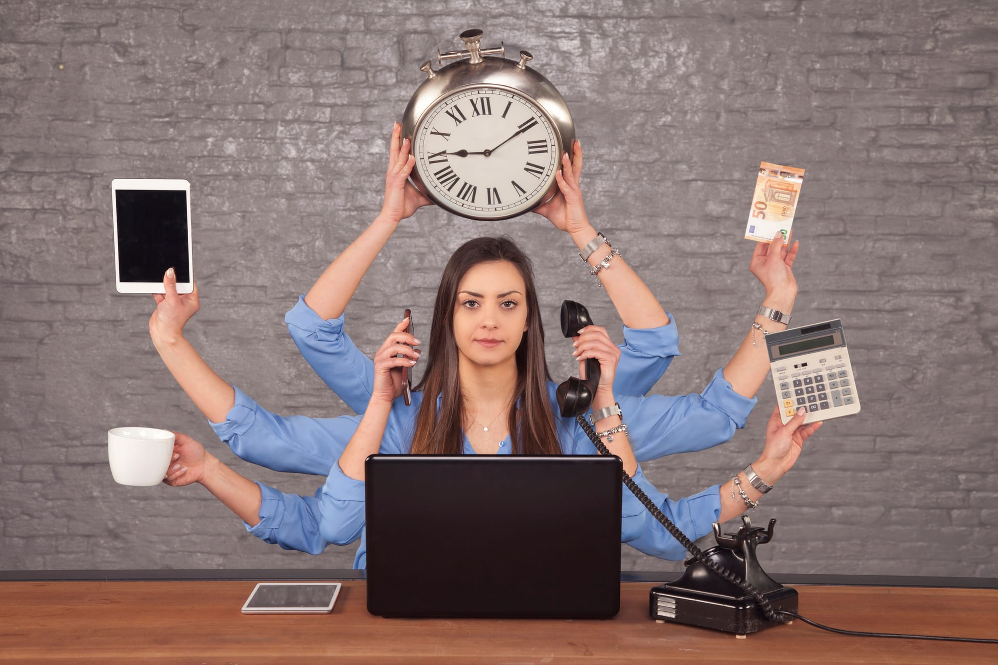 A woman juggling devices at a desk