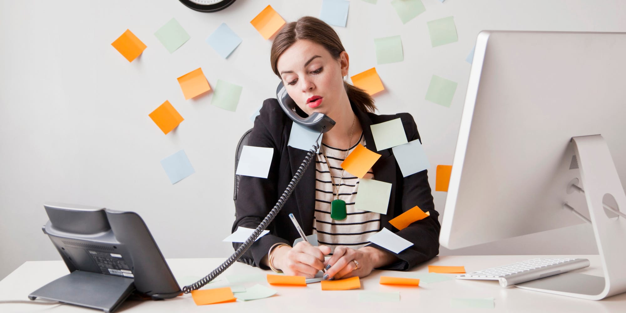 Post it notes and a woman on the phone beside a computer